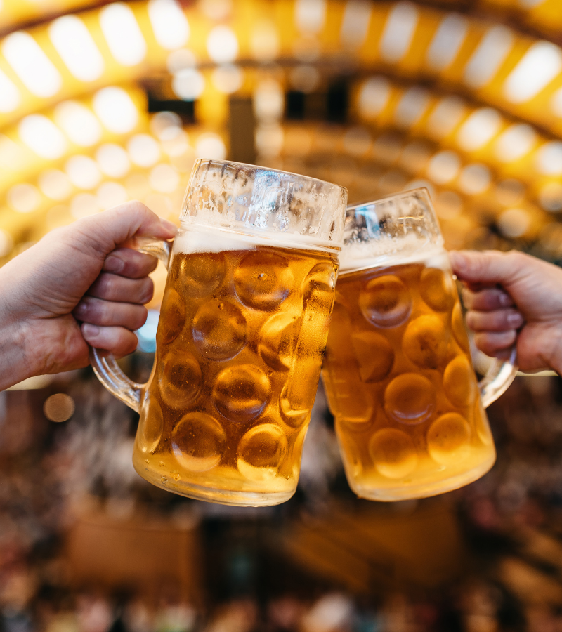 Celebración en el Oktoberfest con dos jarras de cerveza de un litro brindando en la carpa